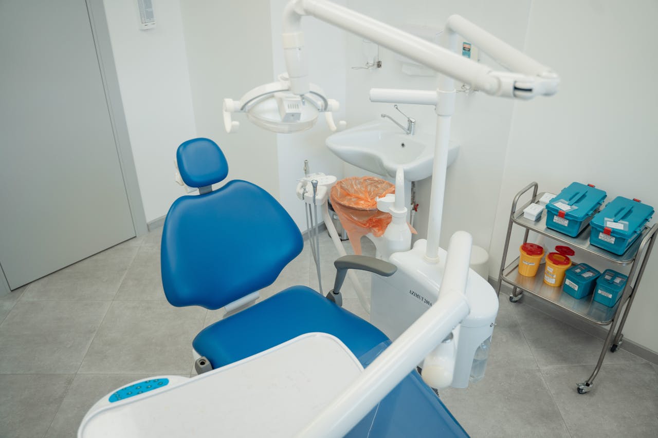 hero-img A clean and modern dental clinic featuring a blue dental chair, equipment, and sterile supplies.